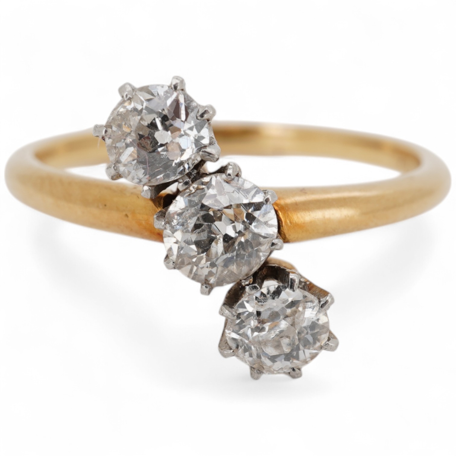 A mid to late 20th century yellow metal and three stone diamond set crossover ring, total diamond weight approx. 0.45-0.50ct, size K, gross weight 2.5 grams.